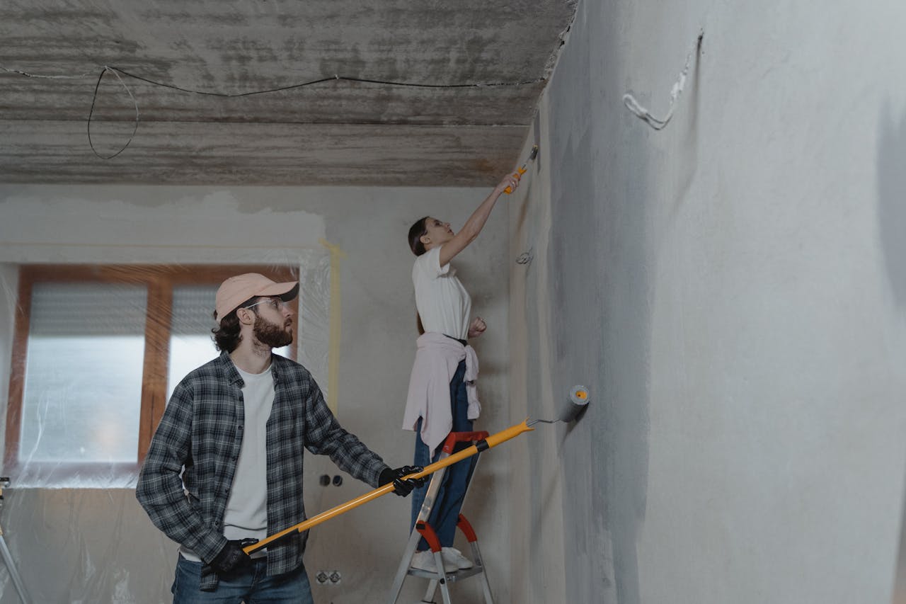 A couple painting a room together, highlighting teamwork in home renovation.